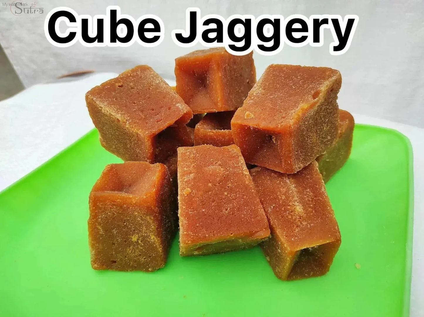 Sutra Jaggery Powder cubes on a green tray; natural sweetener for healthy living.